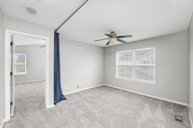 unfurnished room with ceiling fan, carpet, baseboards, and visible vents
