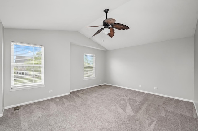 empty room with carpet, visible vents, vaulted ceiling, ceiling fan, and baseboards