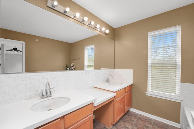 full bathroom with double vanity, decorative backsplash, baseboards, and a sink