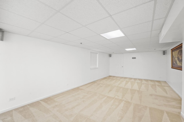 finished basement featuring a paneled ceiling, light carpet, and baseboards