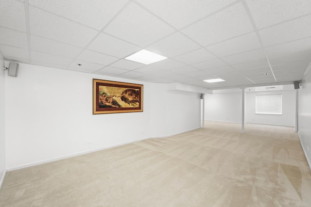 finished basement featuring a paneled ceiling, carpet, and baseboards