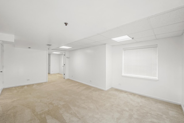 interior space featuring a paneled ceiling, baseboards, and light colored carpet