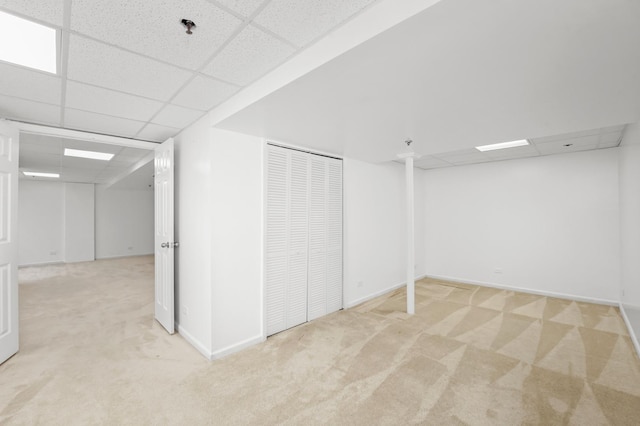 finished below grade area featuring carpet, baseboards, and a paneled ceiling