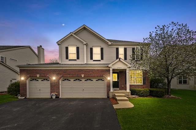 traditional home featuring driveway, roof with shingles, brick siding, and a front yard