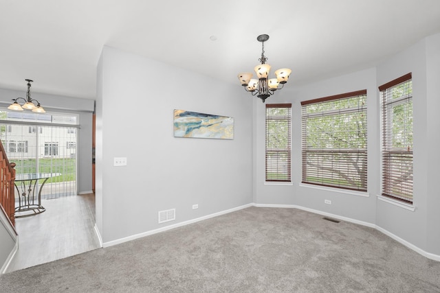 unfurnished room featuring carpet flooring, visible vents, and a notable chandelier