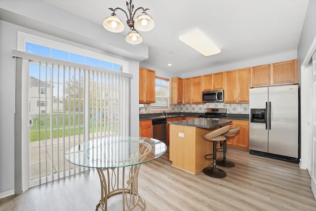kitchen featuring dark countertops, appliances with stainless steel finishes, a kitchen island, and backsplash