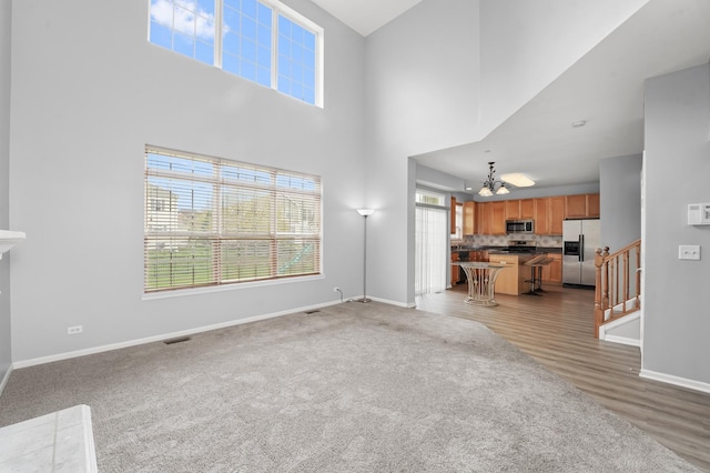living room featuring stairs, a towering ceiling, baseboards, visible vents, and a notable chandelier
