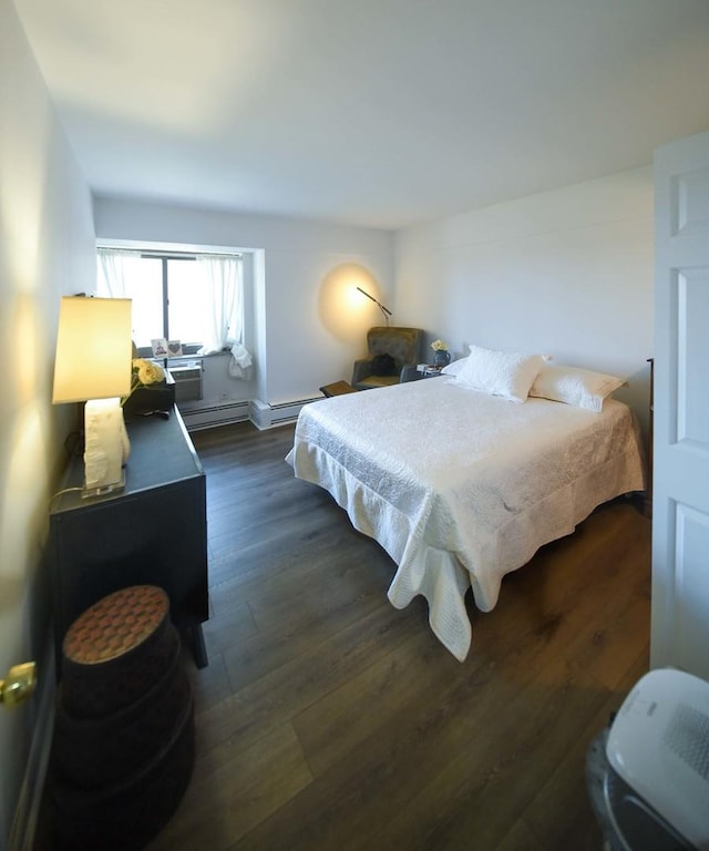 bedroom featuring dark wood finished floors and a baseboard heating unit
