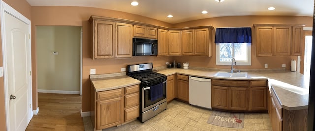 kitchen with gas range, black microwave, dishwasher, light countertops, and a sink