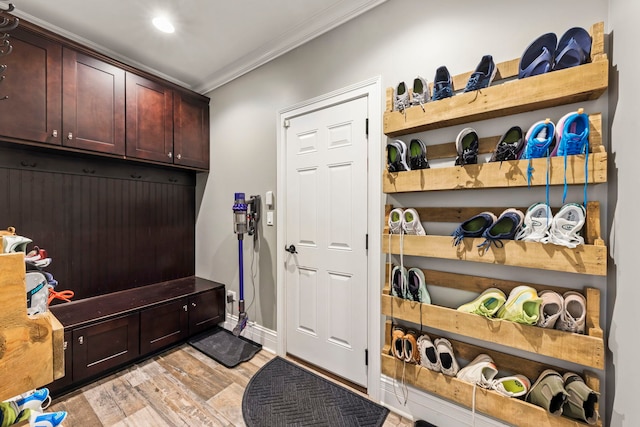 mudroom featuring baseboards, ornamental molding, and light wood finished floors