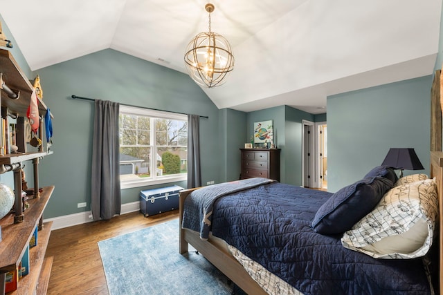 bedroom with an inviting chandelier, baseboards, vaulted ceiling, and wood finished floors