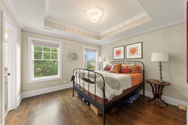 bedroom featuring visible vents, ornamental molding, wood finished floors, and a tray ceiling