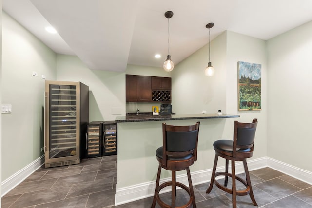 bar with wine cooler, baseboards, and wet bar