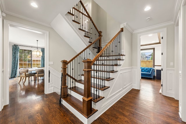 stairway featuring recessed lighting, wainscoting, wood finished floors, and a decorative wall