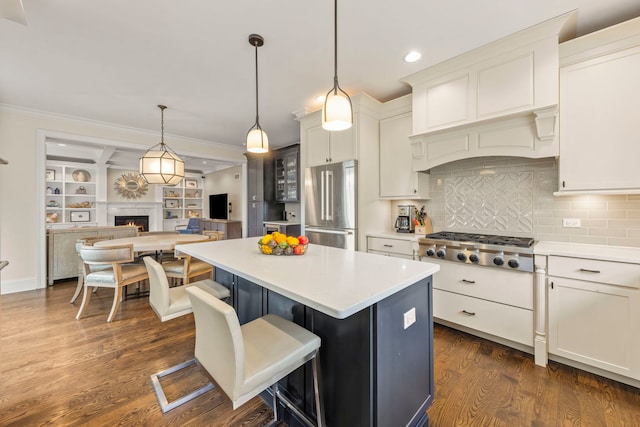 kitchen with decorative backsplash, a center island, light countertops, a warm lit fireplace, and stainless steel appliances