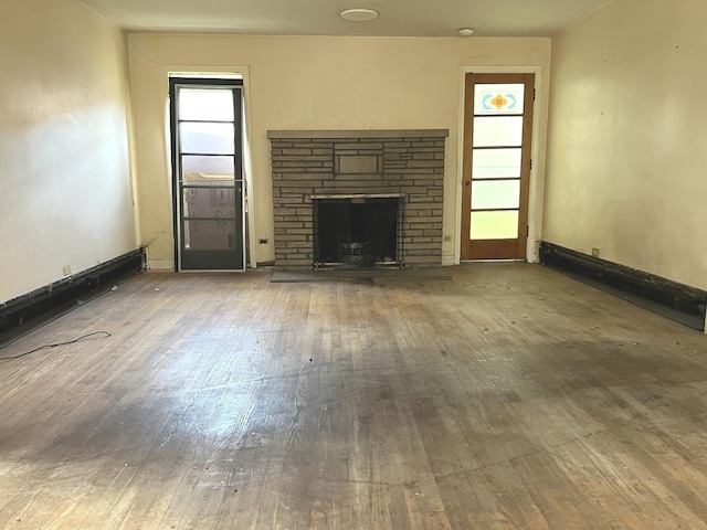 unfurnished living room with wood-type flooring and a fireplace with raised hearth