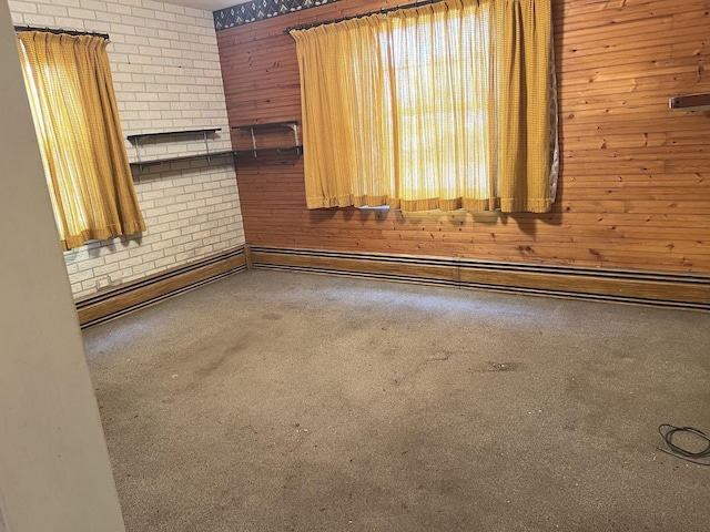 spare room featuring a baseboard heating unit, wood walls, and brick wall