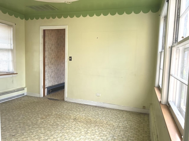spare room with baseboards, a baseboard heating unit, and visible vents