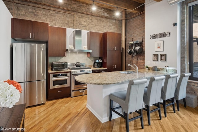 1040 W Adams St Unit 203, Chicago, IL 60607 - kitchen featuring stainless steel appliances, wall chimney range hood, a sink, brick wall, and a towering ceiling