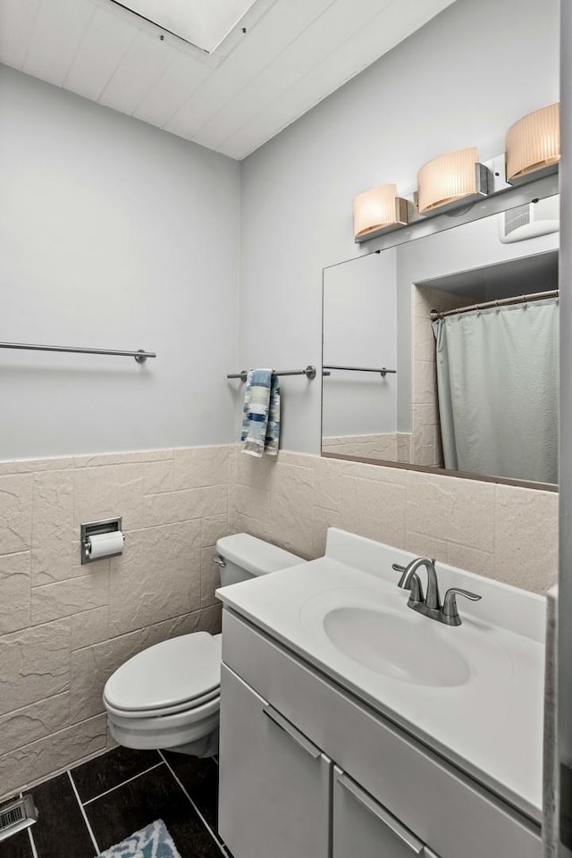 221 Parkview Dr, Bloomington, IL 61701 - bathroom featuring tile walls, toilet, vanity, tile patterned flooring, and a wainscoted wall