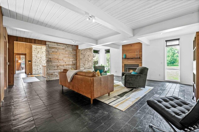 221 Parkview Dr, Bloomington, IL 61701 - living area with track lighting, a lit fireplace, beamed ceiling, wooden walls, and baseboards