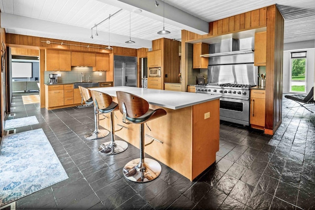 221 Parkview Dr, Bloomington, IL 61701 - kitchen featuring built in appliances, wall chimney range hood, tasteful backsplash, a breakfast bar area, and decorative light fixtures