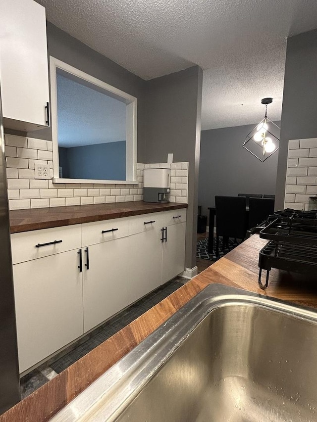 1216 S New Wilke Rd Unit 106, Arlington Heights, IL 60005 - kitchen with wooden counters, a textured ceiling, tasteful backsplash, wood finished floors, and white cabinetry