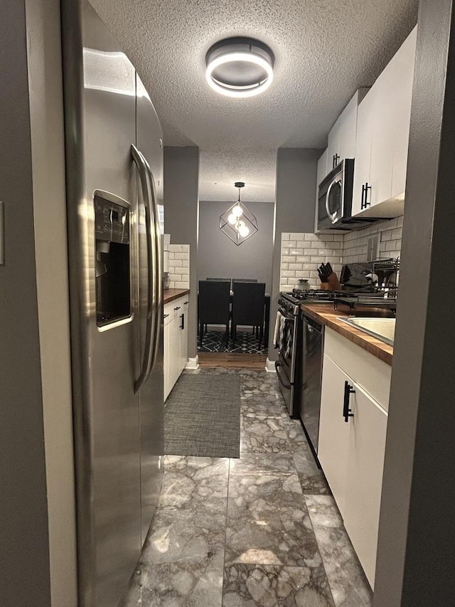 1216 S New Wilke Rd Unit 106, Arlington Heights, IL 60005 - kitchen with a textured ceiling, tasteful backsplash, white cabinetry, and stainless steel appliances