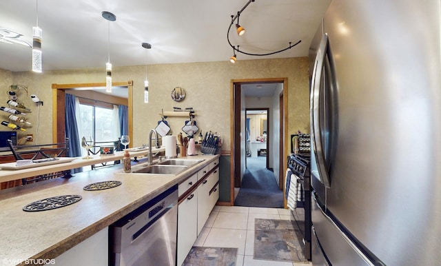 kitchen featuring white cabinets, appliances with stainless steel finishes, a sink, light countertops, and light tile patterned floors