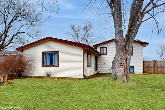 rear view of house with a lawn and fence