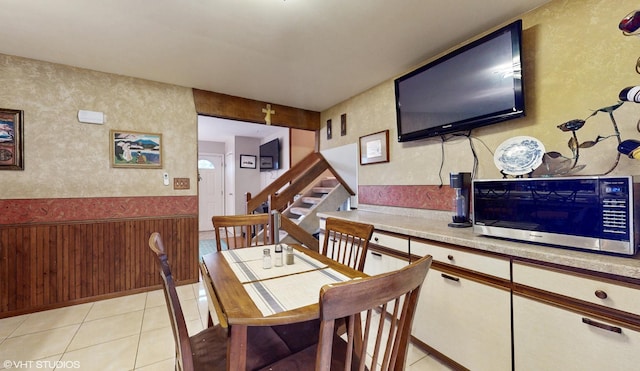 dining room with light tile patterned floors, wainscoting, and stairs