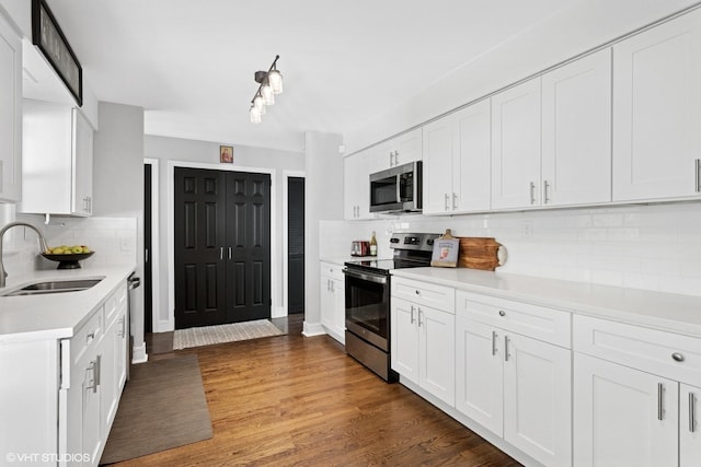 kitchen with stainless steel appliances, a sink, backsplash, light countertops, and white cabinetry