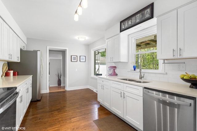 kitchen featuring stainless steel appliances, a sink, tasteful backsplash, and white cabinets