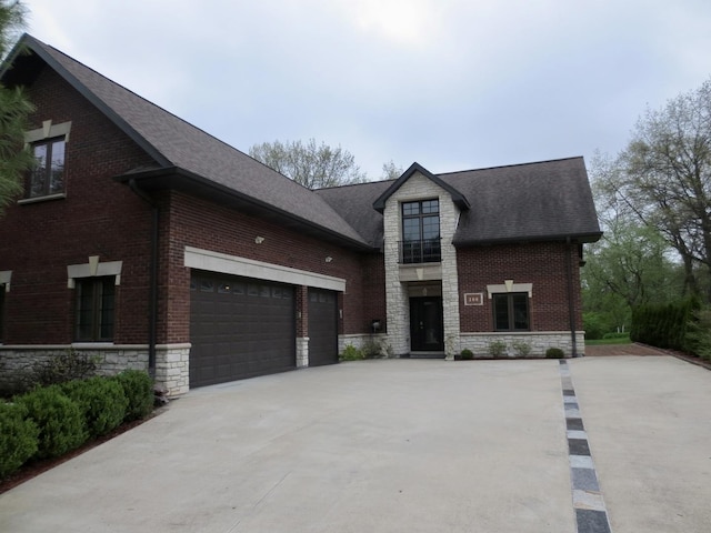 view of front of property with a garage, a shingled roof, stone siding, and concrete driveway