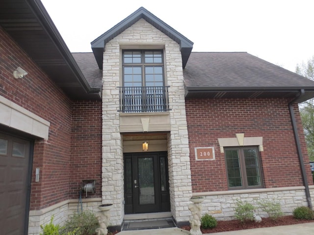 doorway to property featuring brick siding, a shingled roof, and stone siding