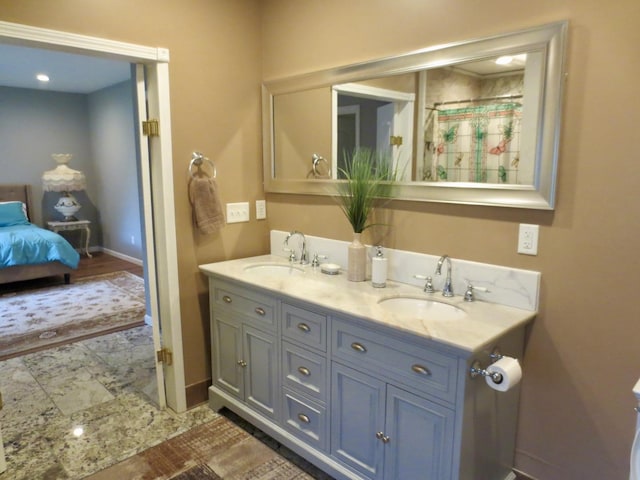 bathroom with double vanity, baseboards, a sink, and ensuite bath