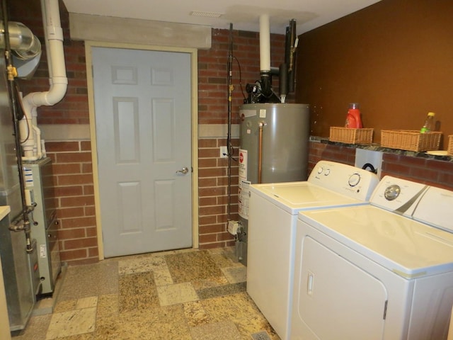 laundry room with laundry area, light floors, washing machine and dryer, and gas water heater