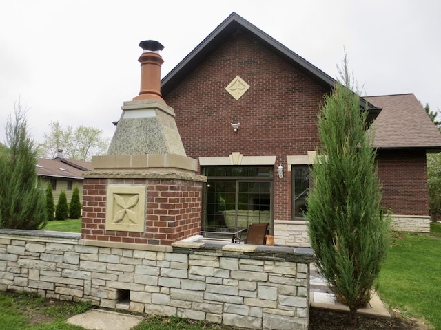 back of property with stone siding, a chimney, and brick siding