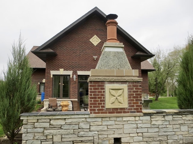 back of property featuring brick siding and stone siding
