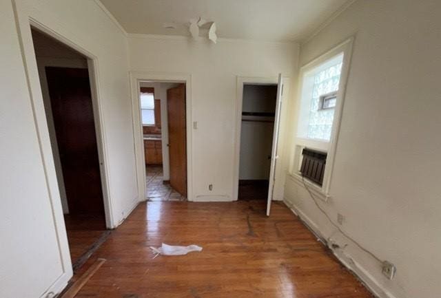 unfurnished bedroom with baseboards, ornamental molding, a closet, and wood finished floors
