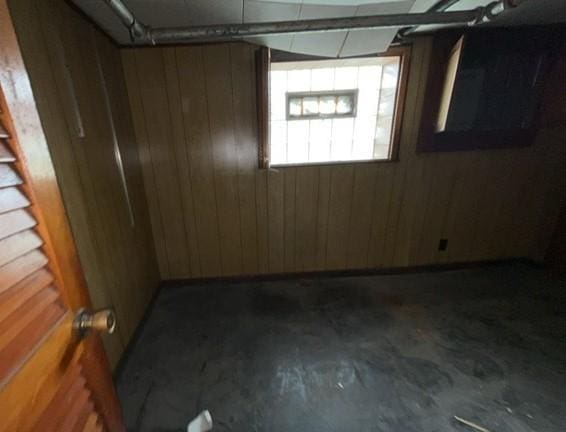 unfurnished room featuring wood walls and concrete floors