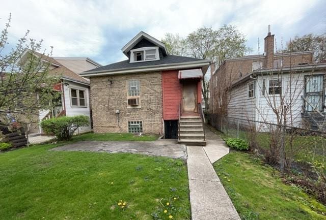 rear view of property featuring fence, a yard, and brick siding