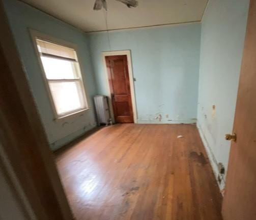 unfurnished room with radiator heating unit, a ceiling fan, and light wood finished floors