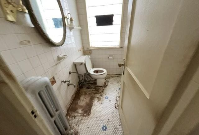 bathroom with toilet and tile walls
