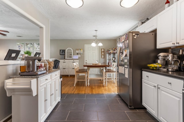 310 S Elm St, Saint Joseph, IL 61873 - kitchen featuring dark countertops, white cabinets, dark tile patterned flooring, stainless steel fridge with ice dispenser, and ceiling fan with notable chandelier