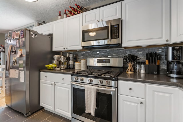310 S Elm St, Saint Joseph, IL 61873 - kitchen featuring dark countertops, tasteful backsplash, stainless steel appliances, and white cabinets