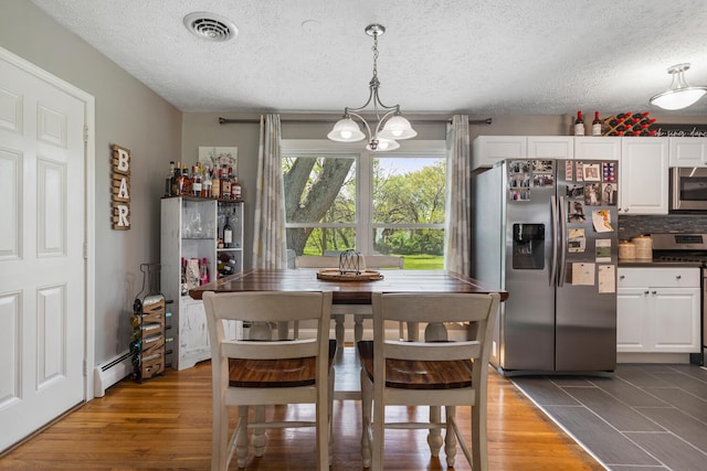 310 S Elm St, Saint Joseph, IL 61873 - dining area featuring a textured ceiling, dark wood-style flooring, a chandelier, and visible vents