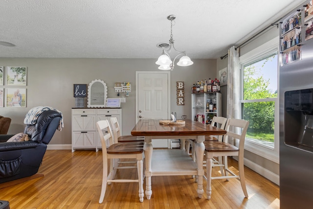 310 S Elm St, Saint Joseph, IL 61873 - dining space featuring baseboards, a textured ceiling, light wood-style flooring, and a notable chandelier