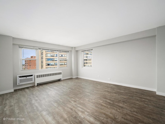 unfurnished living room featuring plenty of natural light, radiator heating unit, and wood finished floors