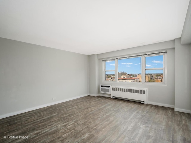 unfurnished room featuring baseboards, a wall unit AC, wood finished floors, and radiator